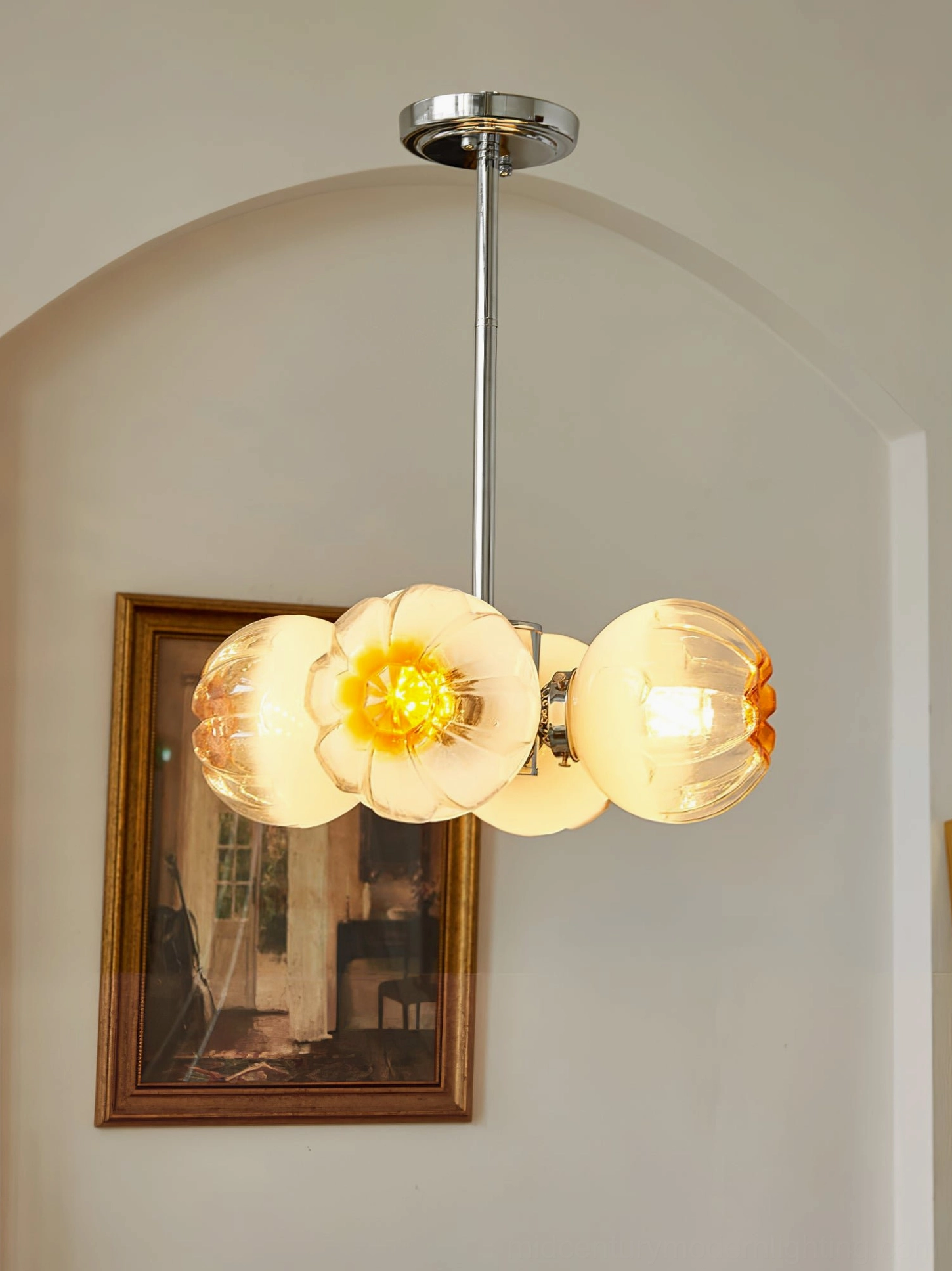 Flower Bud Chandelier displaying warm illuminated amber glass shades in French vintage interior with framed art