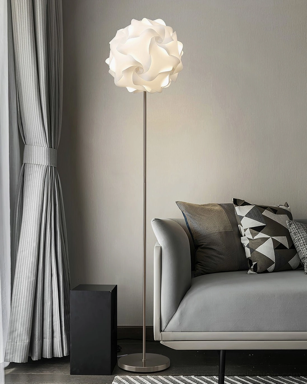 Contemporary flower floor lamp creating warm ambient lighting in cozy minimalist living room with gray sofa