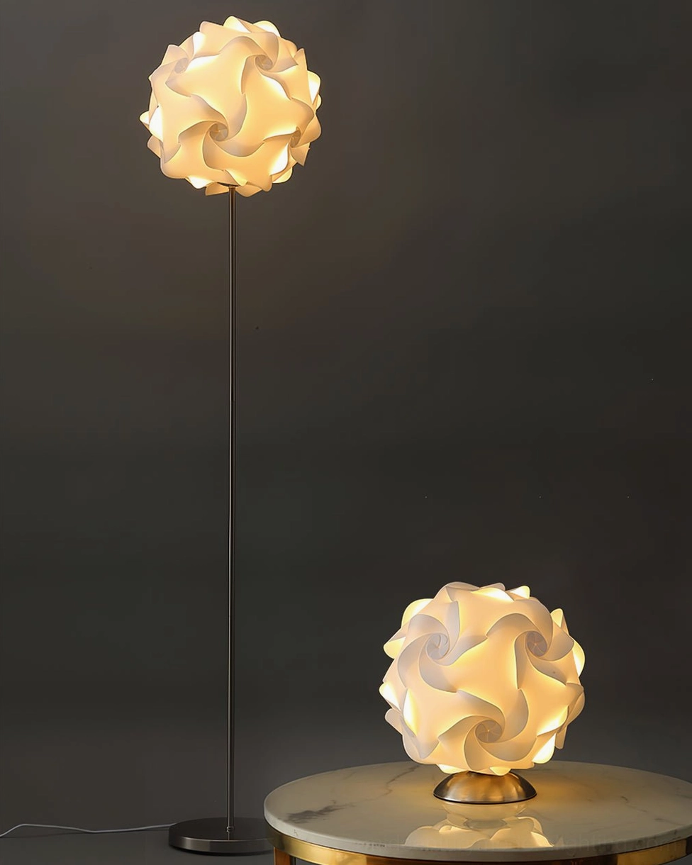 Flower-shaped floor lamp and matching table lamp with warm glowing shade on dark background