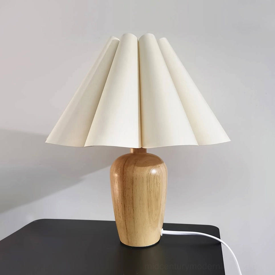 Pleated beige table lamp front view studio shot on black table showcasing sculptural fabric folds and wood base design