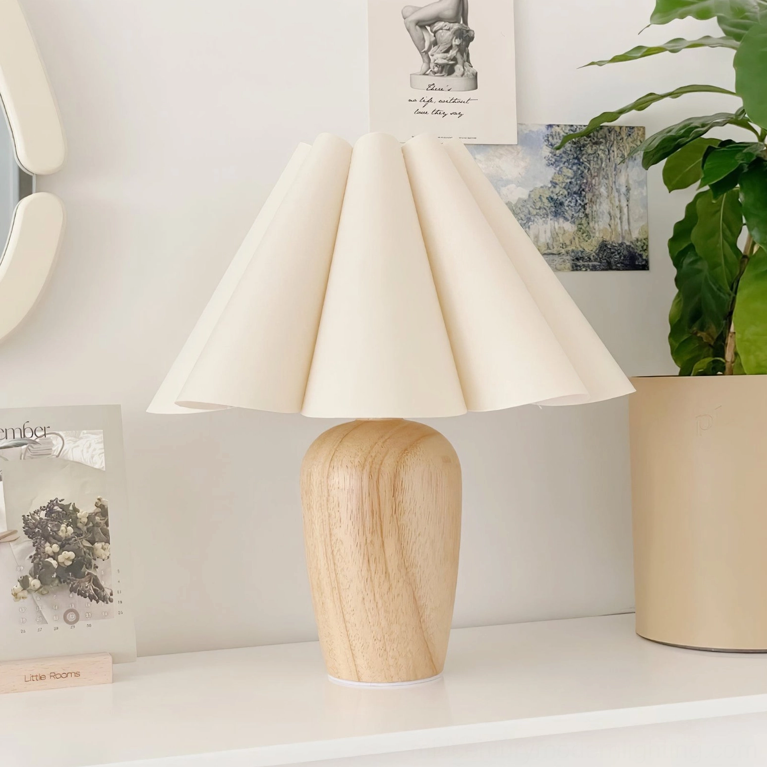 Beige pleated fabric table lamp displayed on home shelf with three-quarter angle view in boho minimalist interior styling