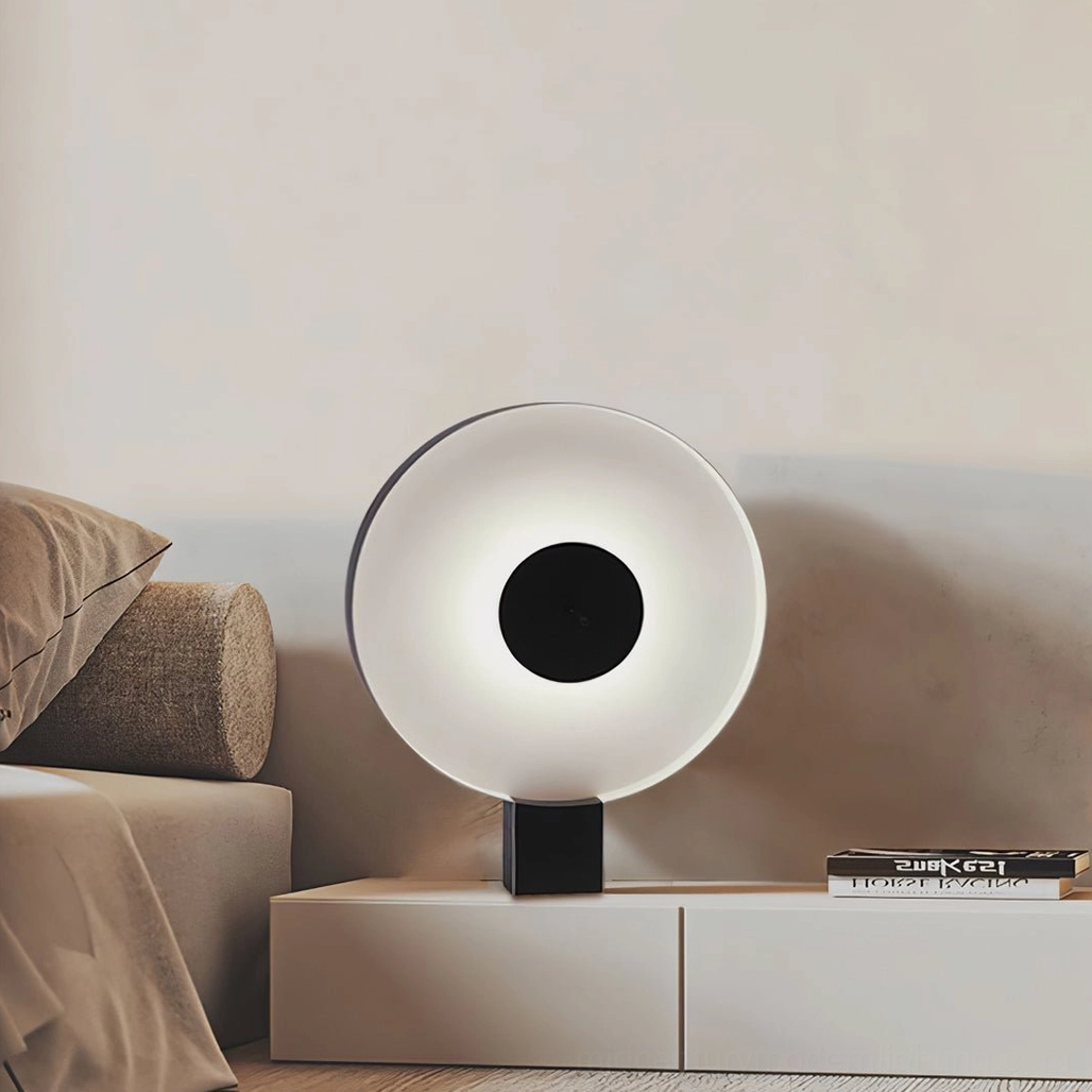 Round Flying Saucer table lamp placed on white cabinet in modern bedroom with sofa, side angle view