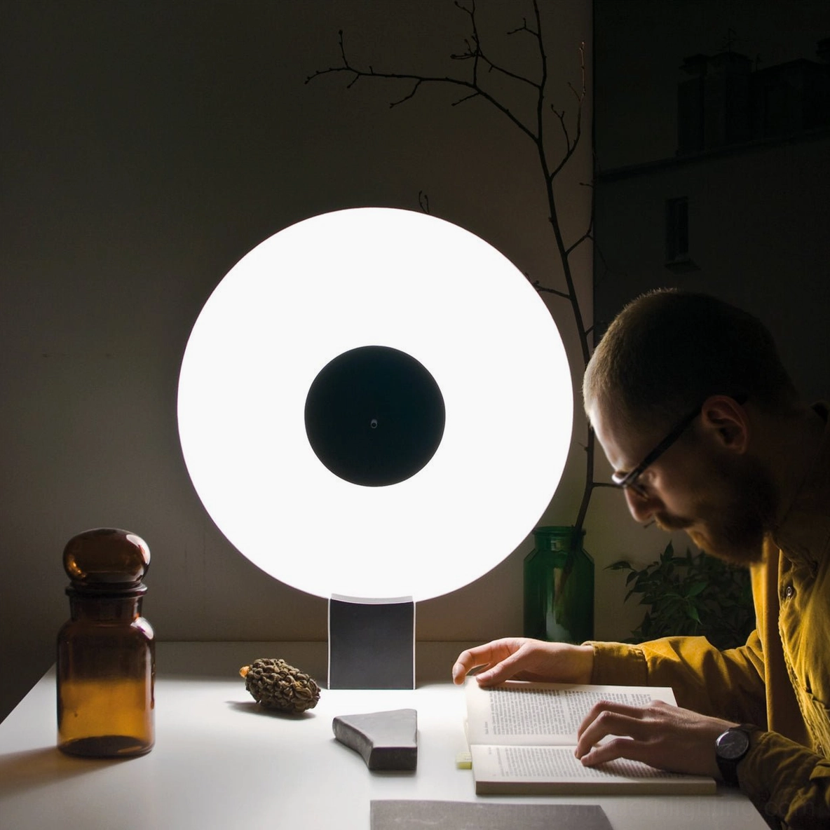 Man reading at desk illuminated by Flying Saucer lamp's warm task lighting, home office nighttime setup
