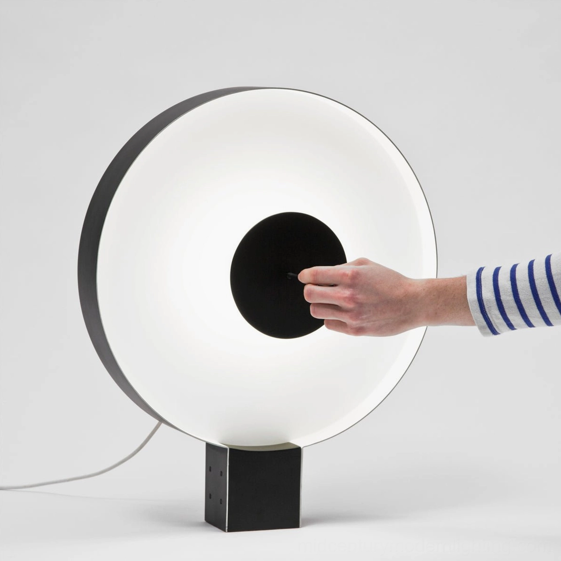 Hand adjusting Round Flying Saucer lamp's rotating disc mechanism, demonstrating dimmable control feature