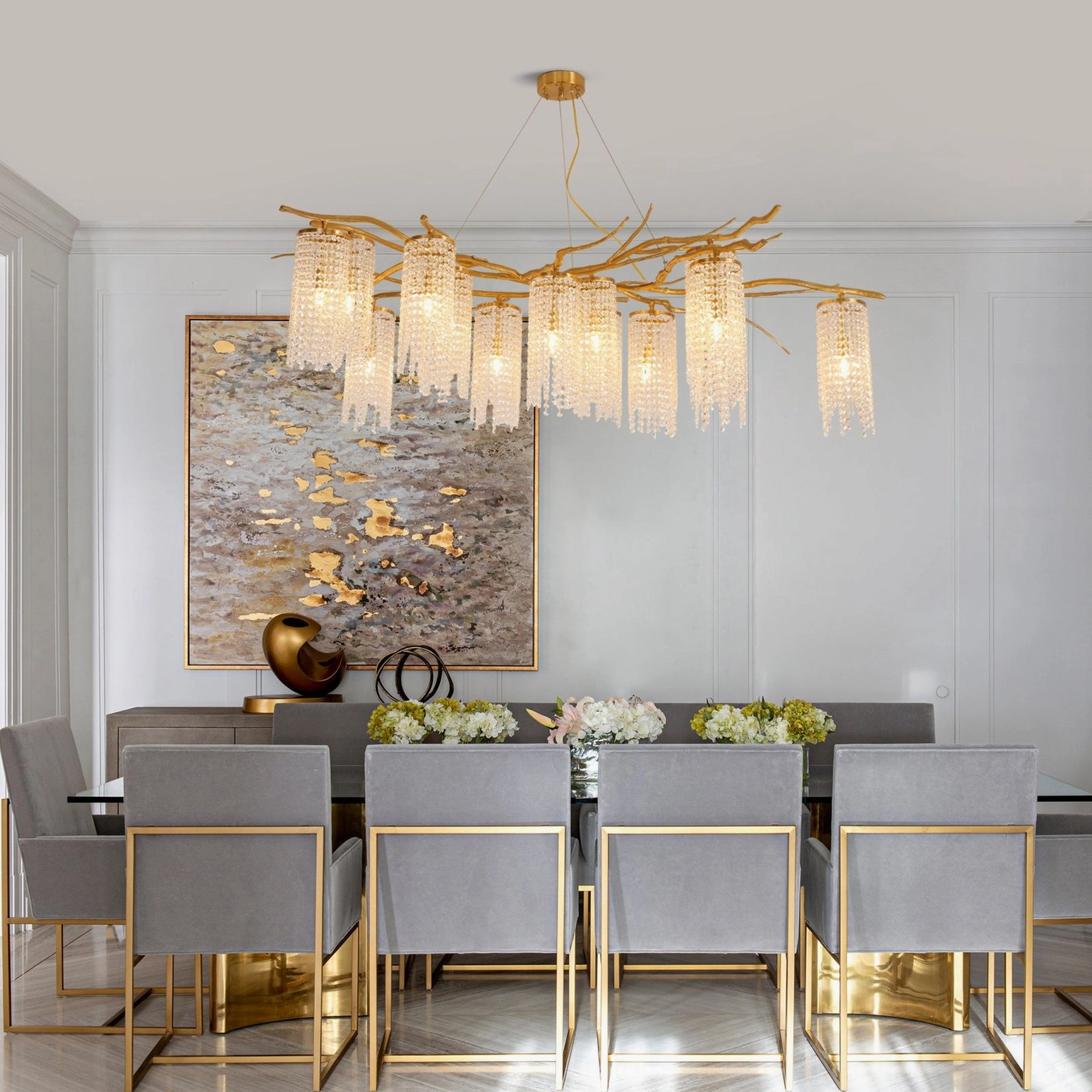 Forest Dawn Chandelier illuminated in modern luxury dining space with wall art and warm golden branch structure
