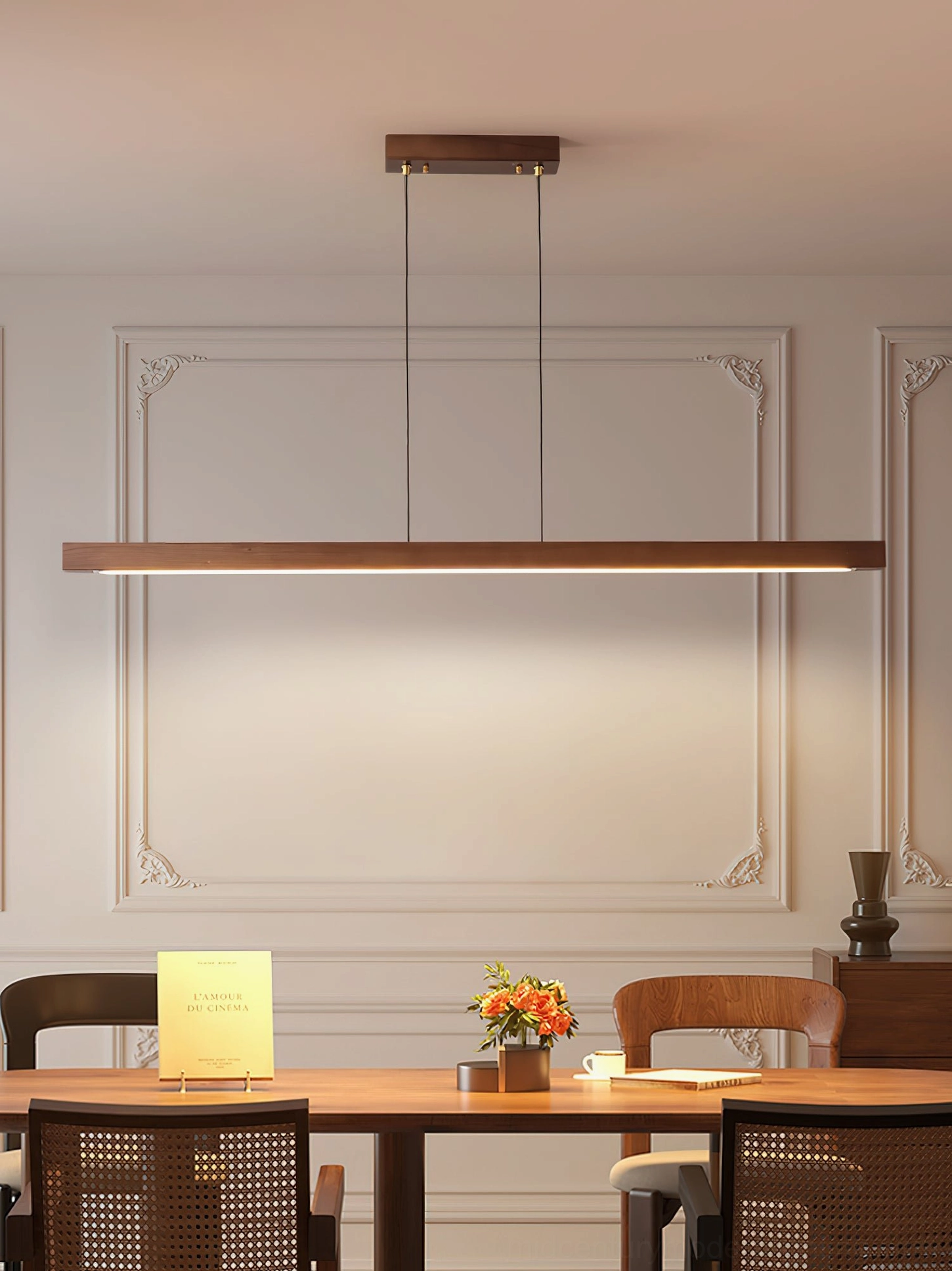 Dark walnut linear chandelier illuminated in classic formal dining room with traditional wall trims and elegant setting