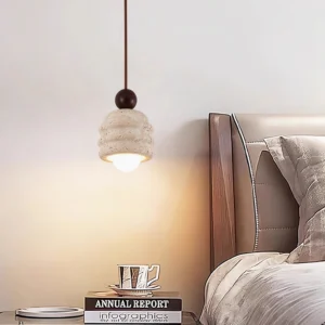 Fossil pendant light hanging above bedroom bedside table in warm ambient lighting, showcasing how travertine stone glows in bedroom interior design