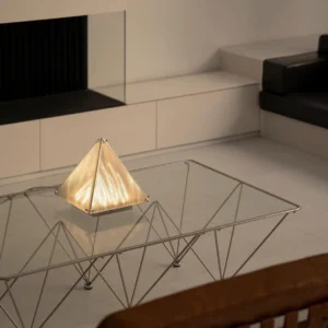 Modern pyramid table lamp creating warm ambient lighting in contemporary minimalist living room setting