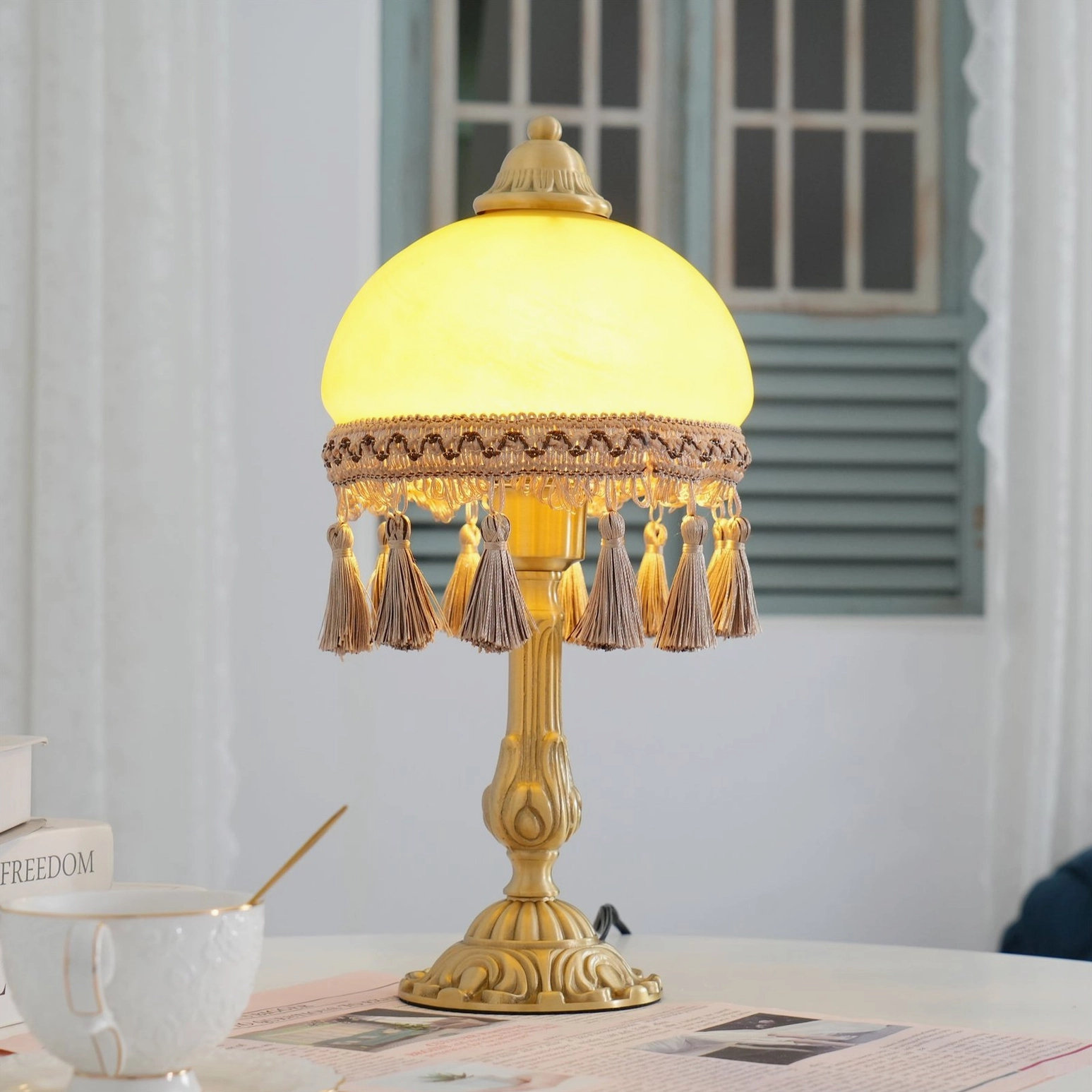 French style brass table lamp on bright home desk with window shutters and natural light