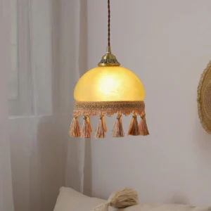 Vintage French tassel pendant light hanging in warm bohemian bedroom lounge setting with ambient lighting