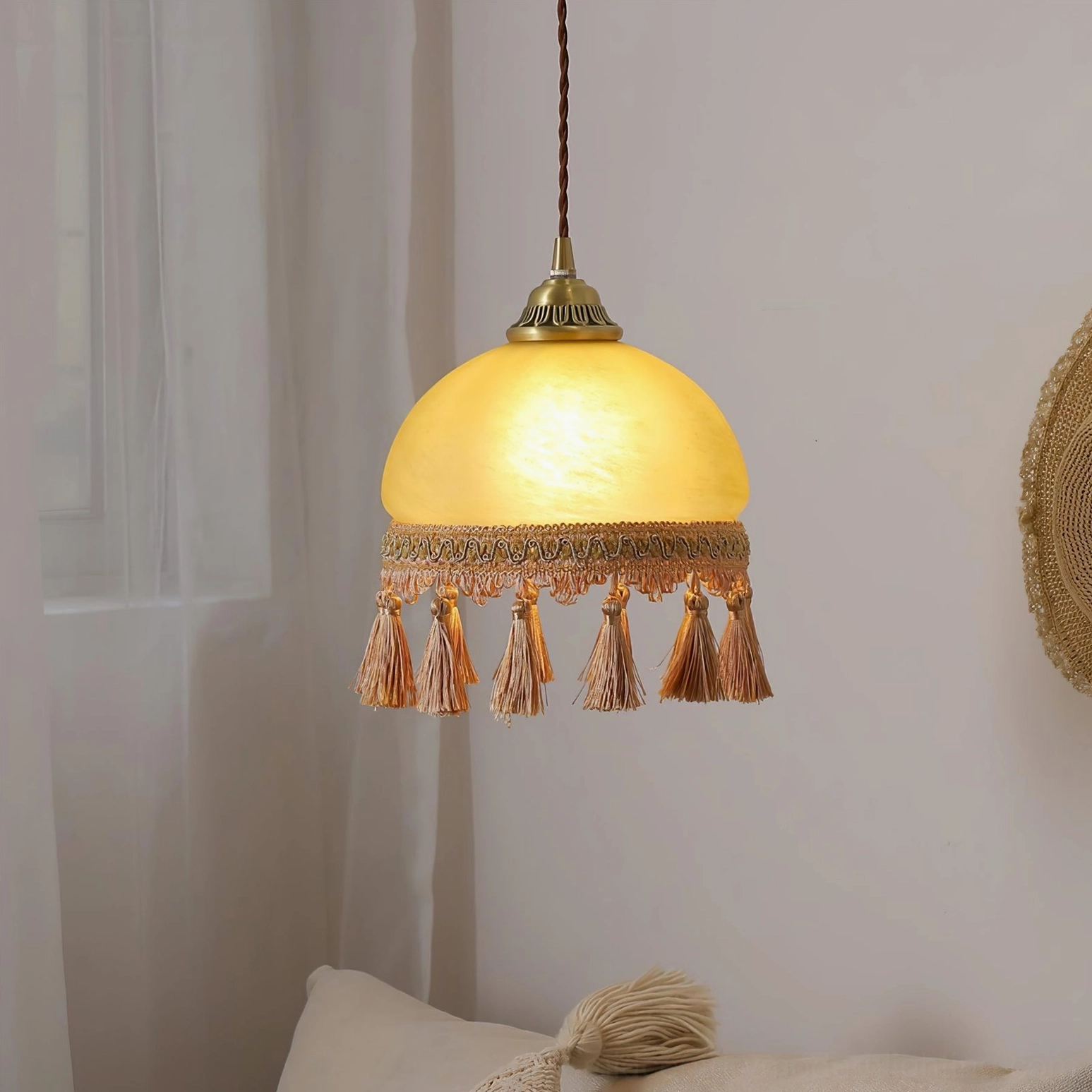 Vintage French tassel pendant light hanging in warm bohemian bedroom lounge setting with ambient lighting