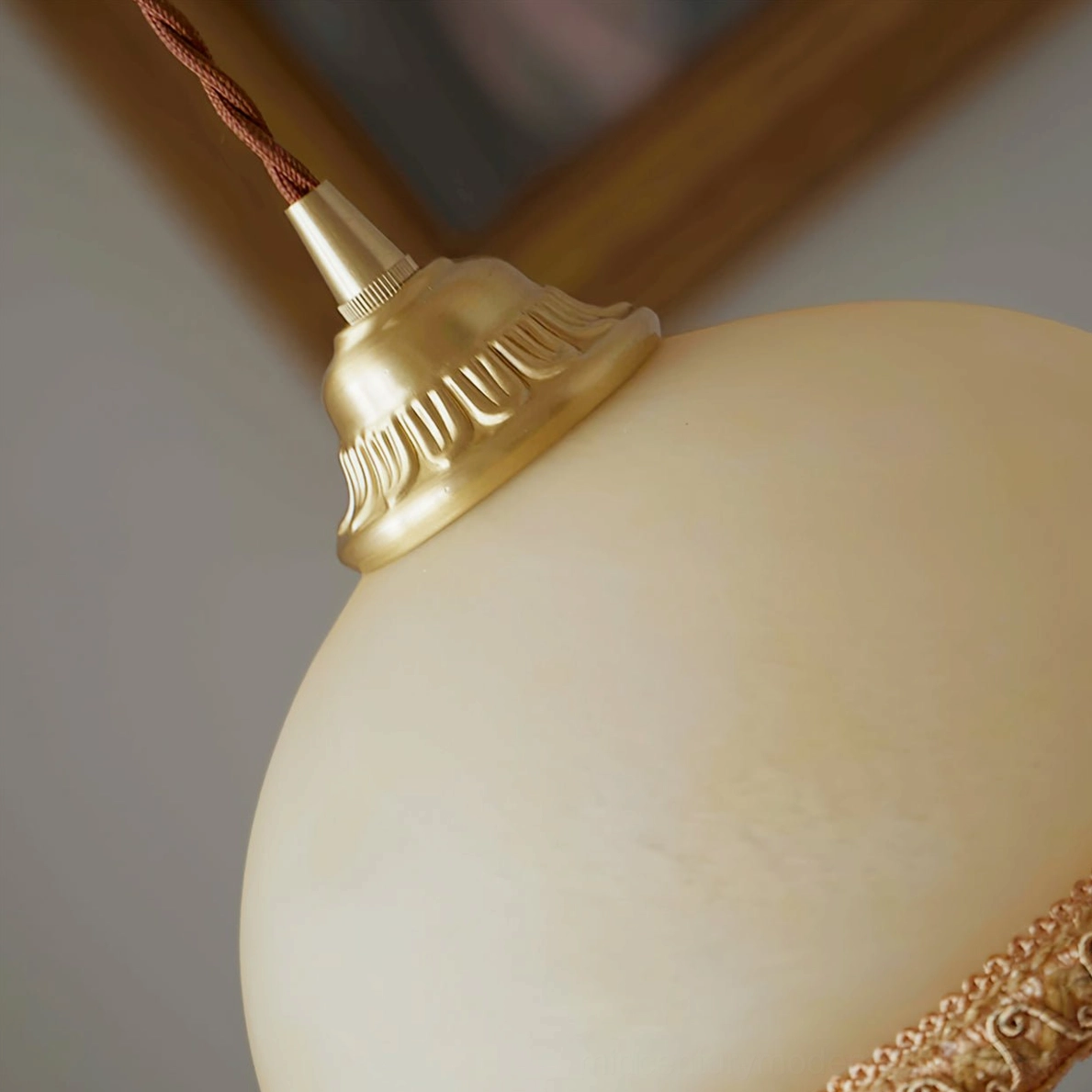 Top brass hardware detail of French tassel pendant light showing polished brass with braided cloth cord