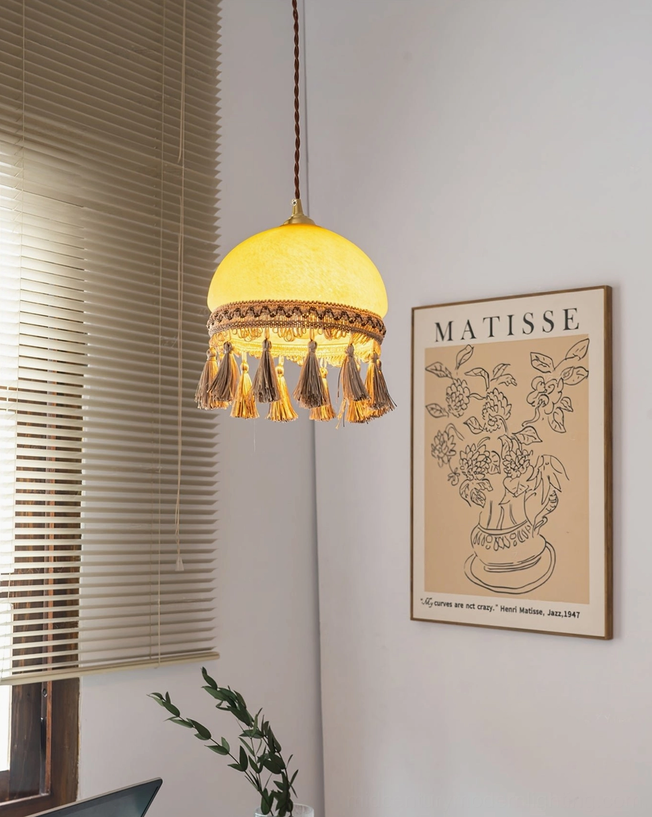 French tassel brass pendant light in home office with warm bohemian styling and art print wall