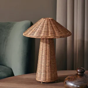 Freya rattan mushroom table lamp three-quarter view beside teal velvet sofa, warm woven texture, mid-century modern living room