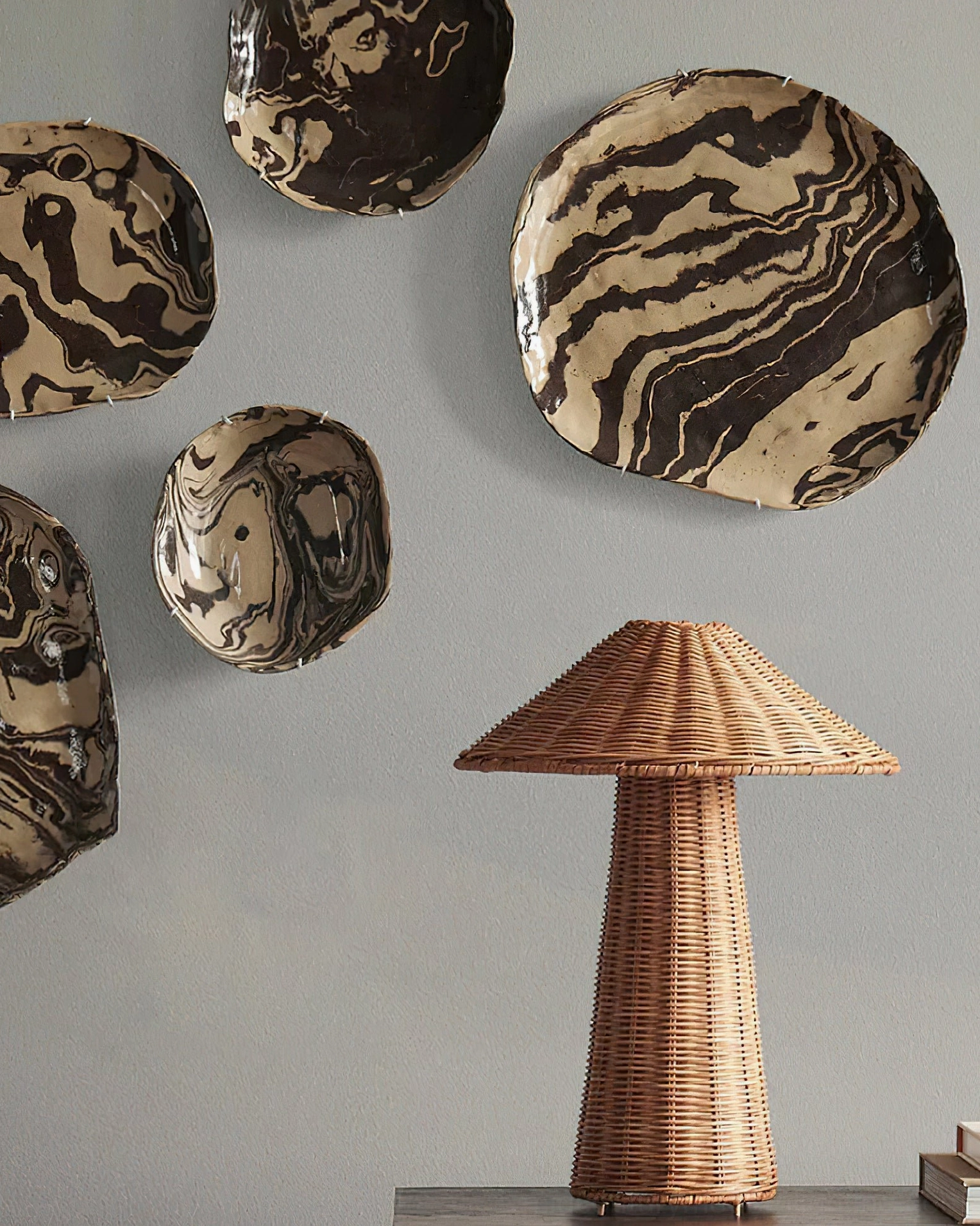 Freya rattan table lamp three-quarter front view dark wooden side table, marbled ceramic wall art, neutral earthy tones