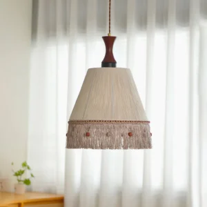 Boho pendant lamp with cotton thread fringe hanging in minimalist room with white sheer curtains