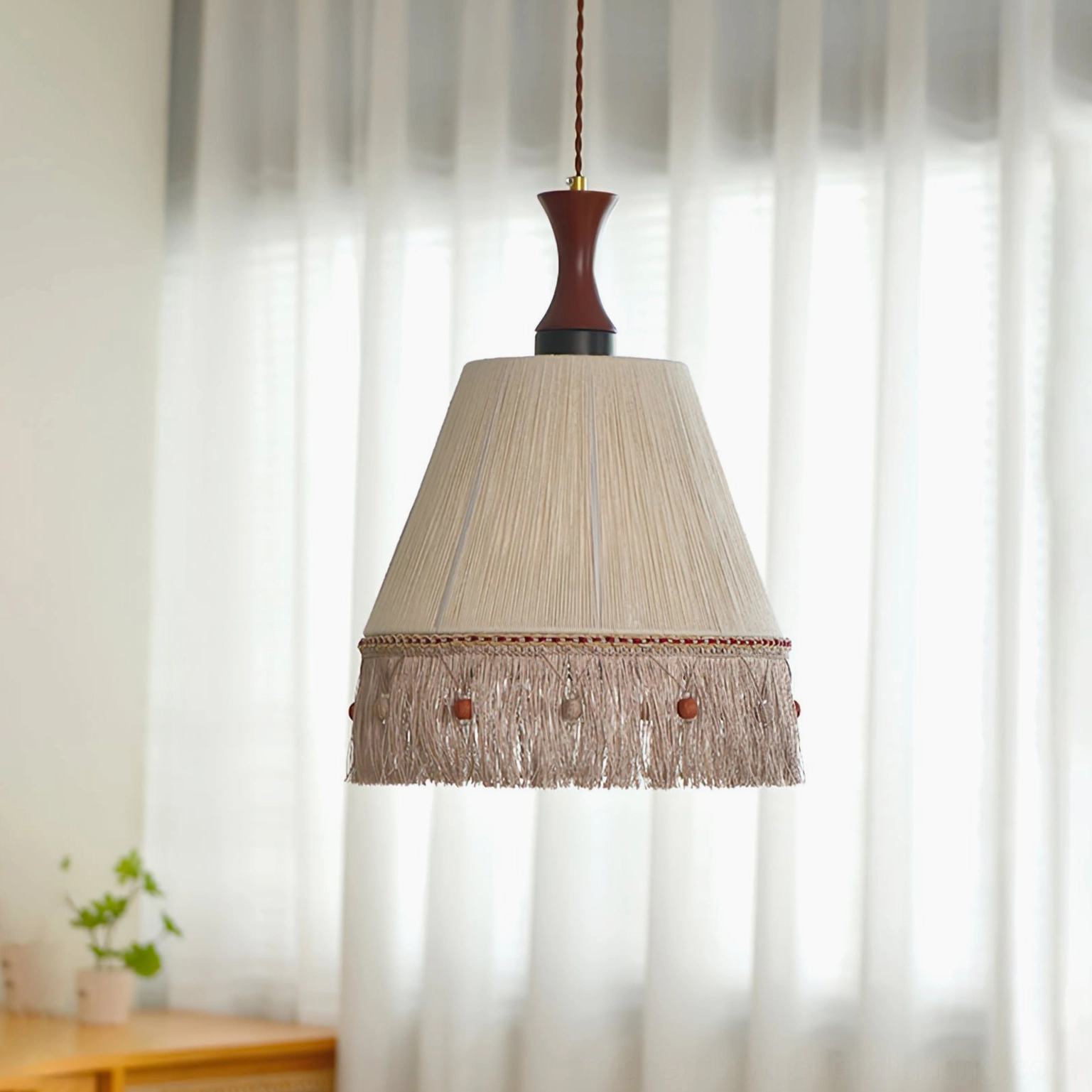 Boho pendant lamp with cotton thread fringe hanging in minimalist room with white sheer curtains