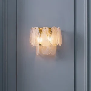 Modern cloud glass wall lamp mounted on grey textured wall, lit with warm amber glow showing wavy translucent glass details