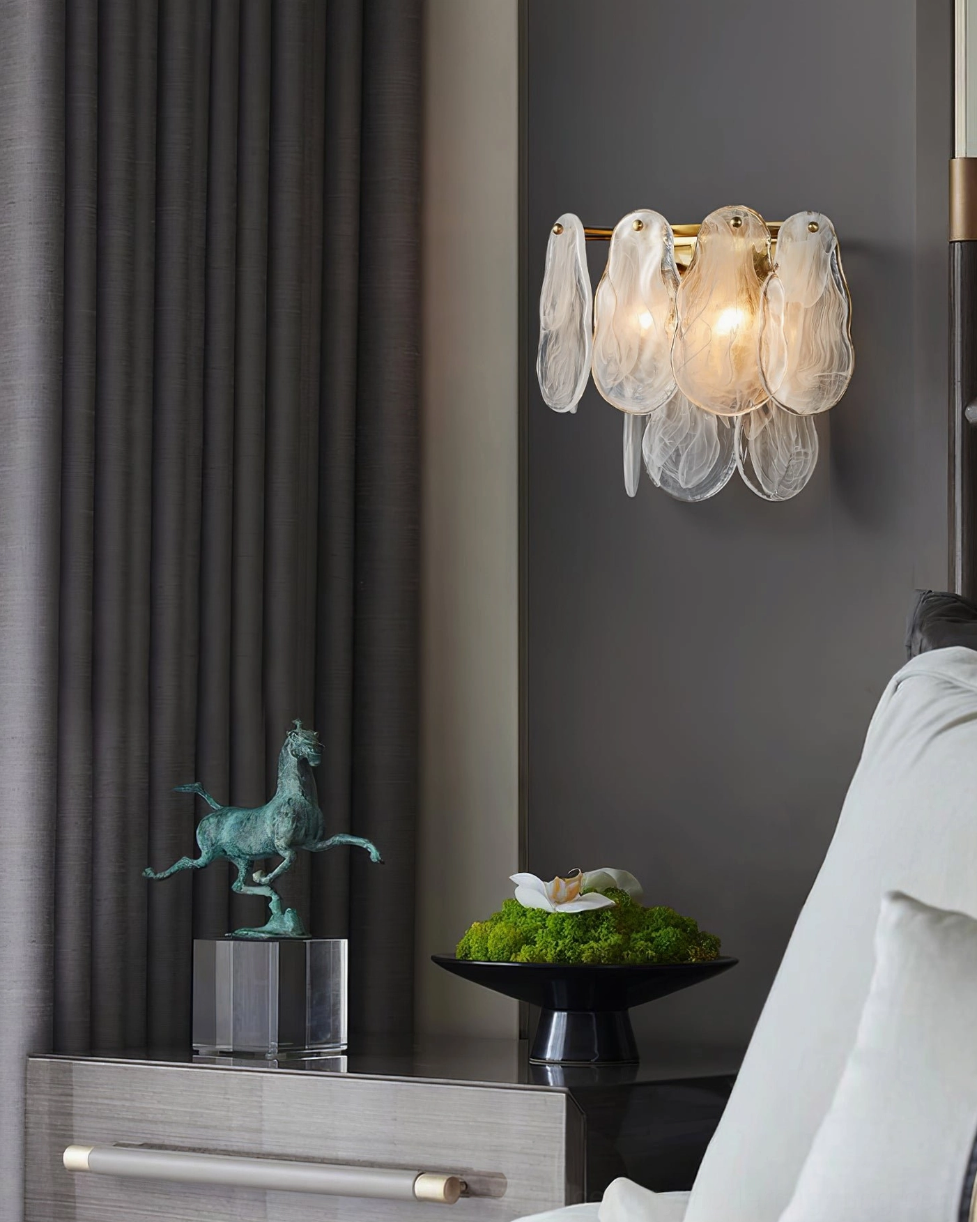 Frosted cloud glass wall lamp with brass base near decorative cabinet, side angle showing unlit glass petal shades and hardware details