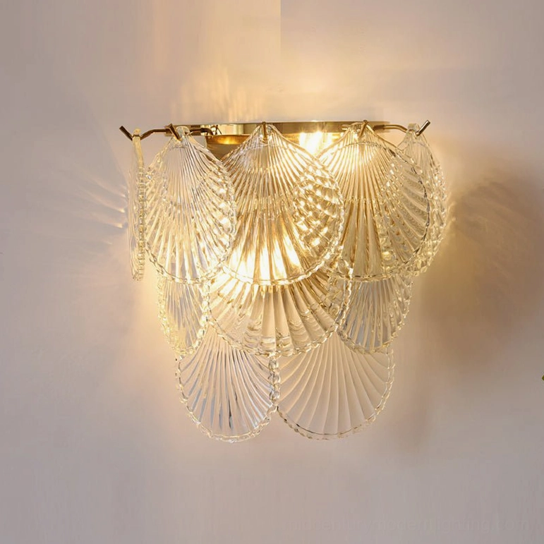 Galerie wall sconce close-up featuring clear textured glass shell and gold base with warm illumination