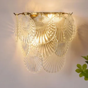 Galerie wall sconce with clear textured glass and gold base, warm light illuminated indoors