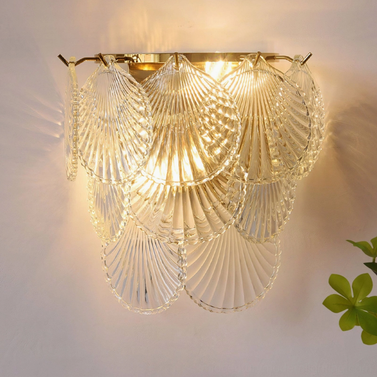 Galerie wall sconce with clear textured glass and gold base, warm light illuminated indoors