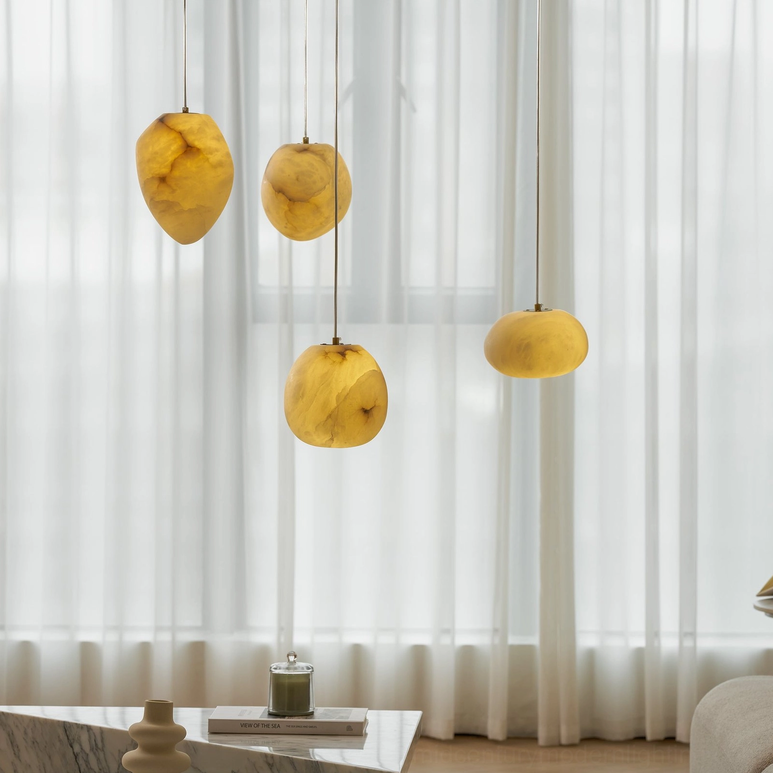 Galet alabaster pendant light glowing warm amber in modern living room with sheer curtains