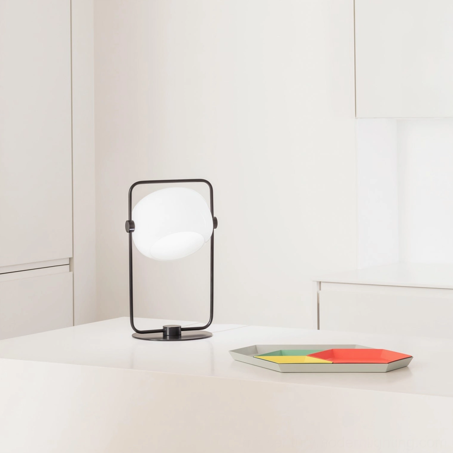Black geometric table lamp on minimalist white desk with decorative accessories