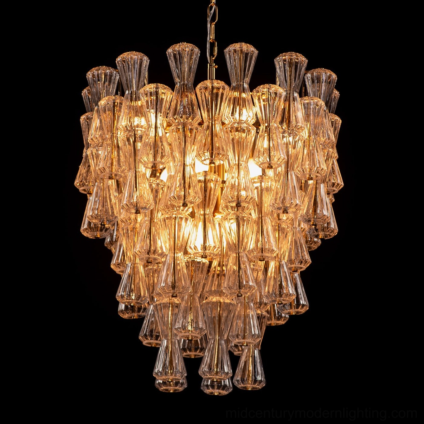 Lit amber tiered glass Garrick Hourglass Chandelier angled view highlighting prismatic light patterns