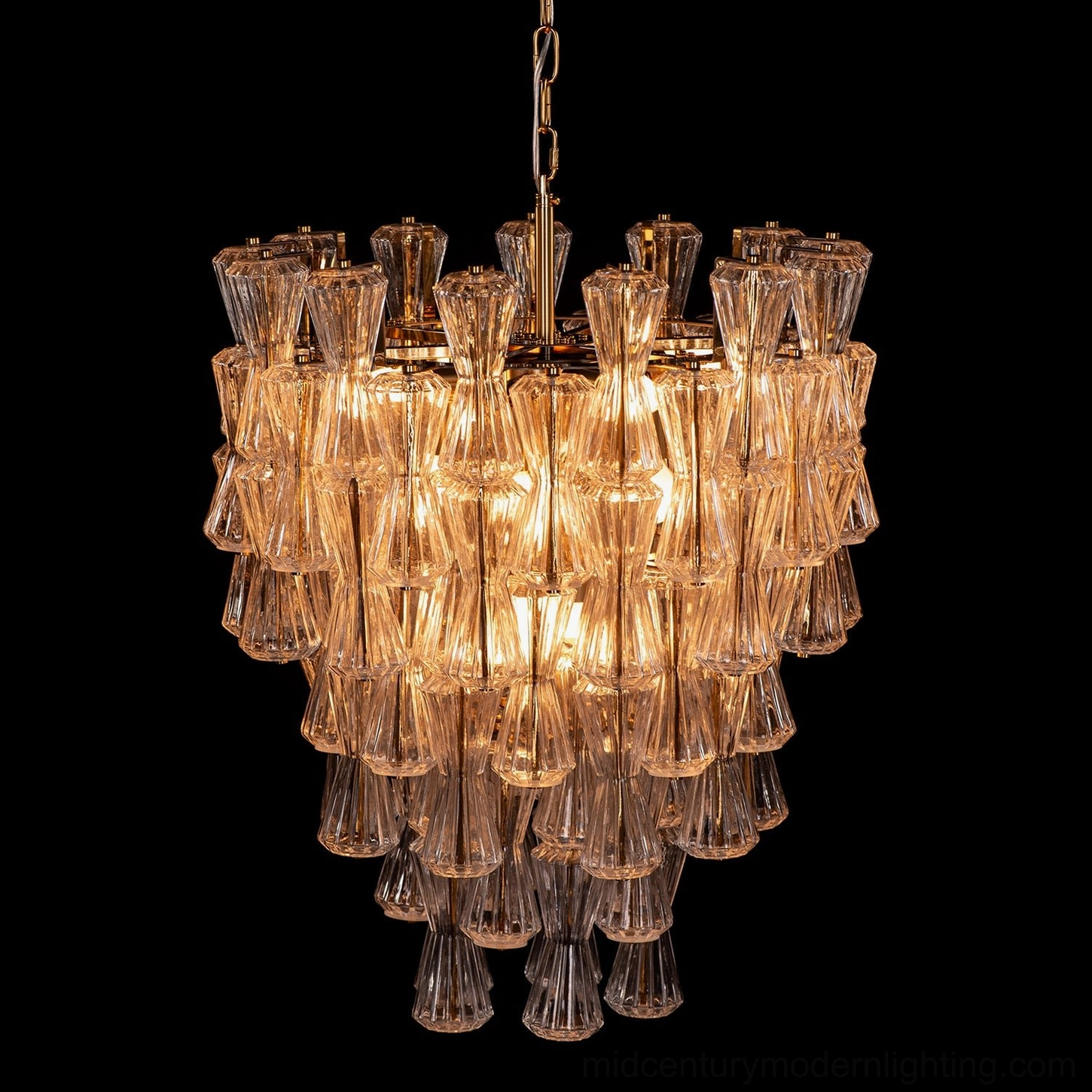 Illuminated amber glass Garrick Hourglass Chandelier close-up on black background showing light refraction