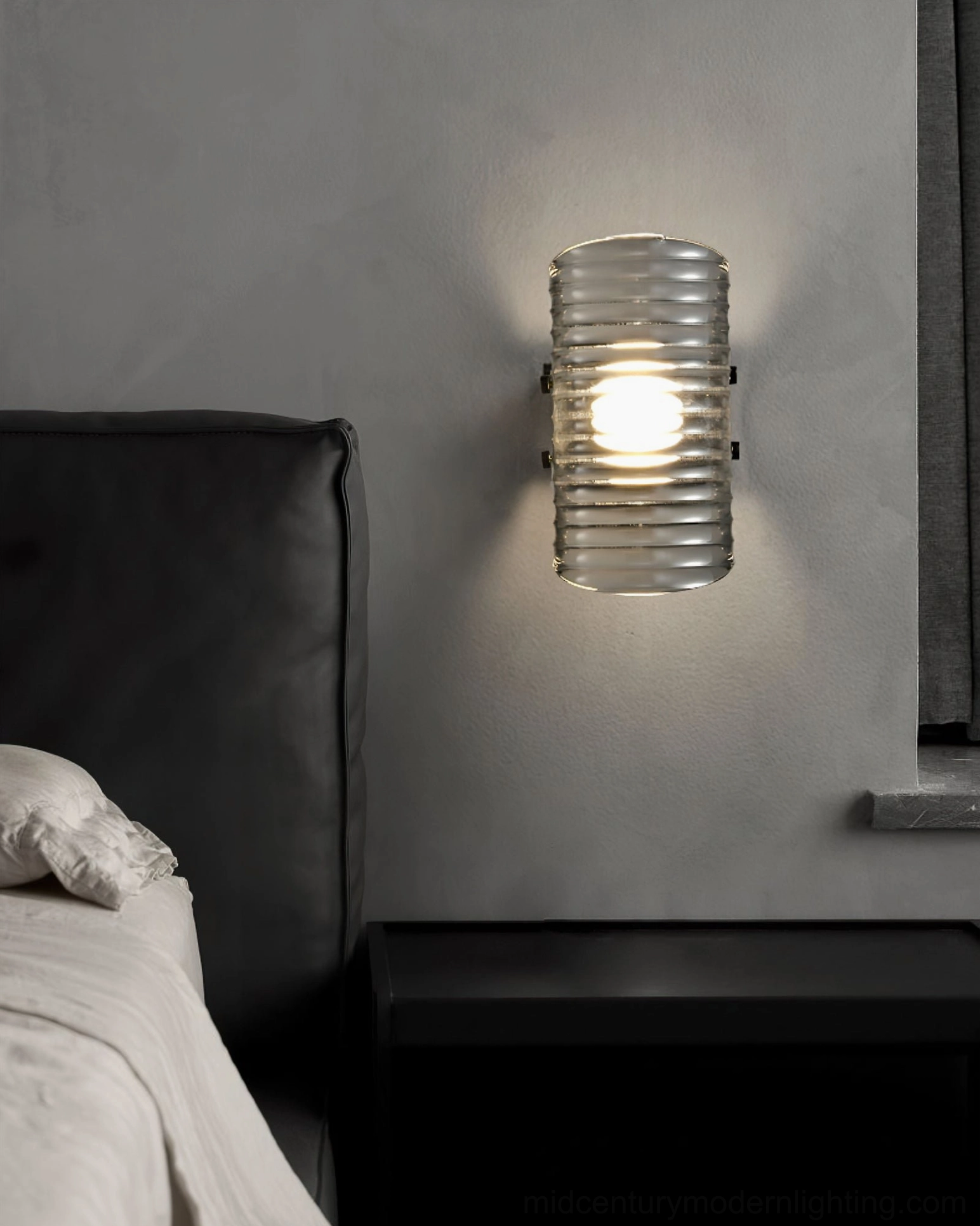 Gatsby cylindrical ribbed glass wall lamp installed in bedroom above bedside table, contemporary minimalist bedroom lighting design