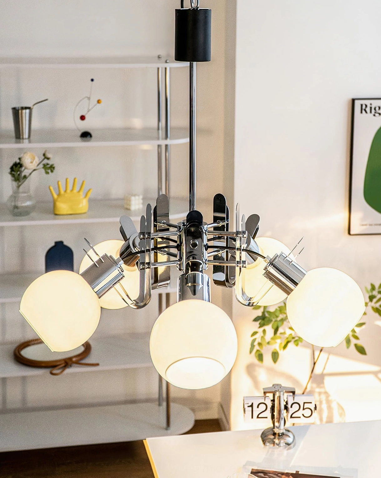 Lit geometric glass chandelier with warm ambient lighting above decorative shelving and ornaments