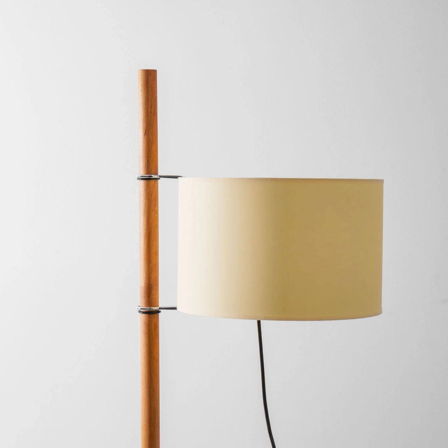Wooden floor lamp with geometric cross base in clean modern interior space