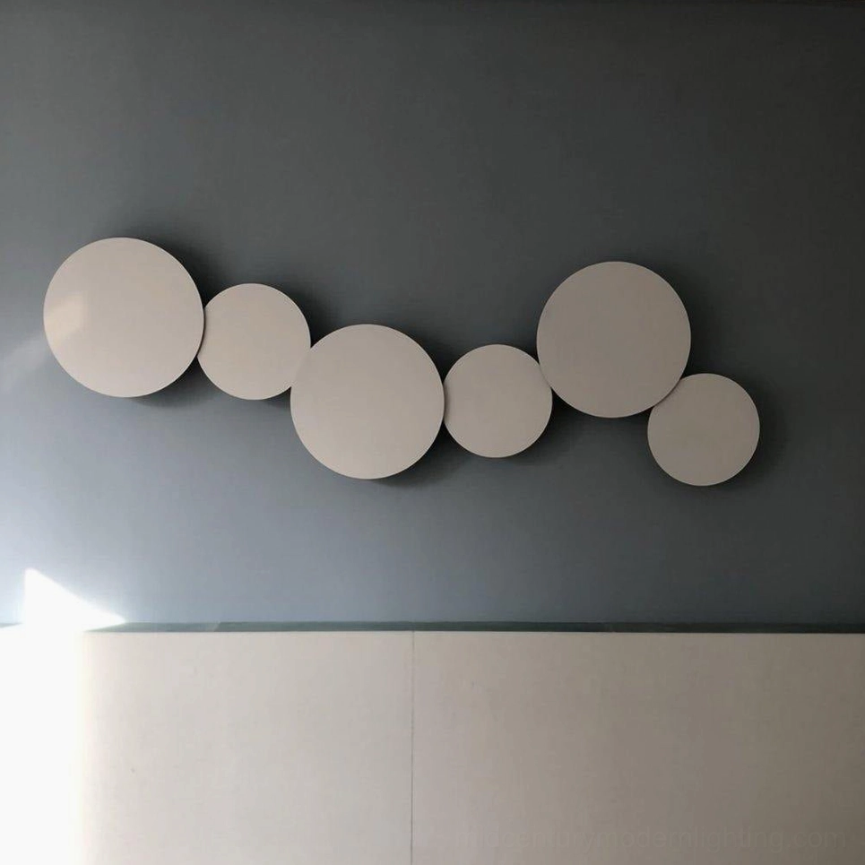 Contemporary geometric disc wall installation in minimalist space creating soft ambient warm light atmosphere