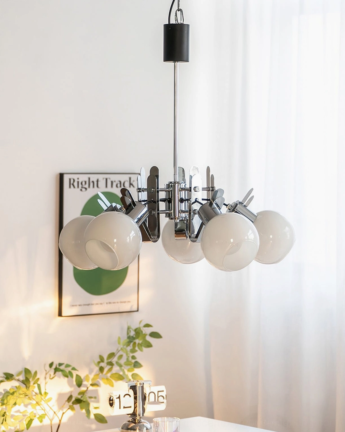 Geometric glass chandelier hanging from ceiling with sheer curtains creating ambient lighting in home interior