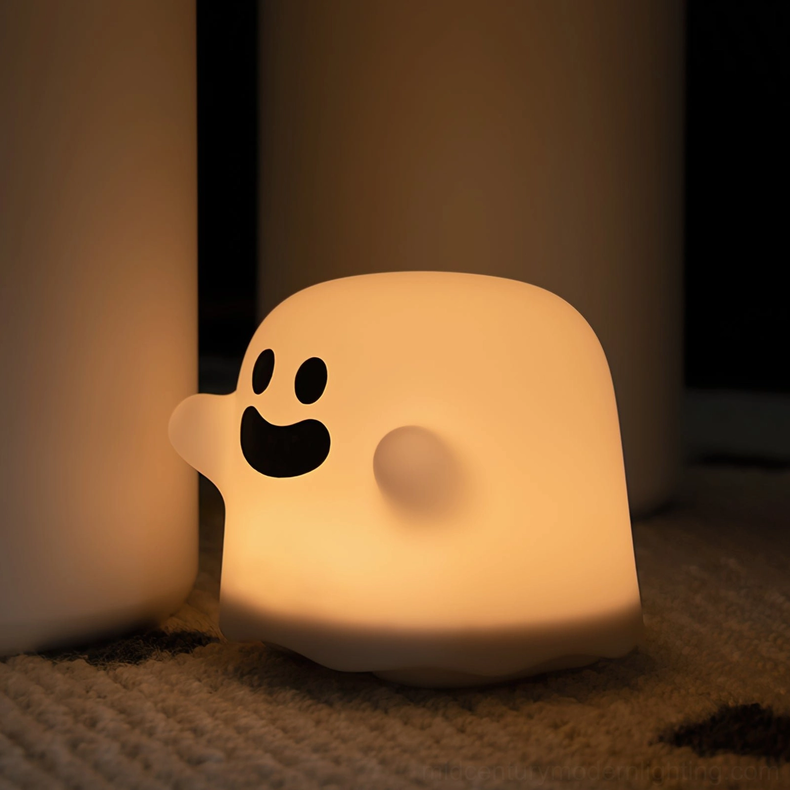 Ghost silicone night light with smiling face glowing warm light on indoor floor with minimalist rug setting