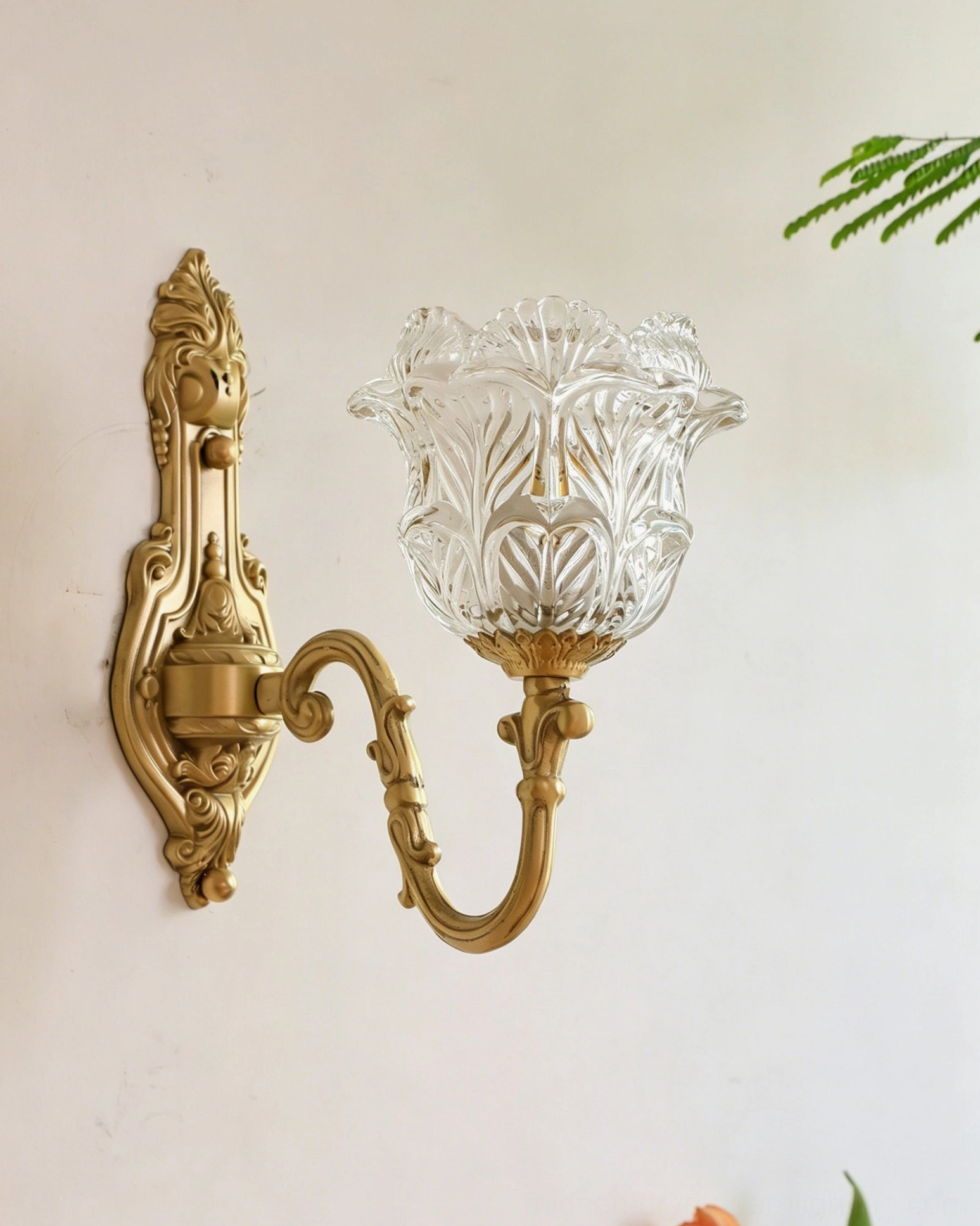 Left frontal view of Gideon Baroque wall sconce showing S-curve scroll arm, ornate brass base with leaf details, and floral glass shade