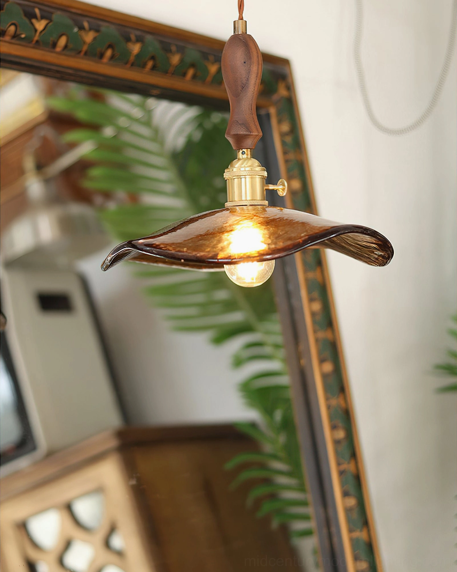 Three-quarter side angle of Gideon mid-century modern pendant in vintage living room setting with decorative mirror and warm lighting