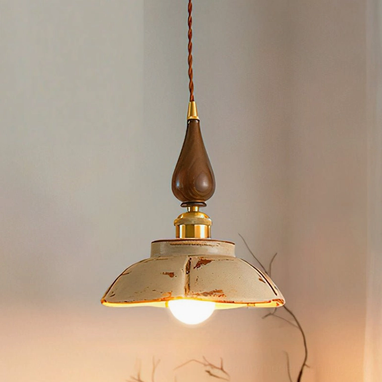Gigaro pendant light with worn brass patina, ruffled ceramic shade, and twisted fabric cord on plain background