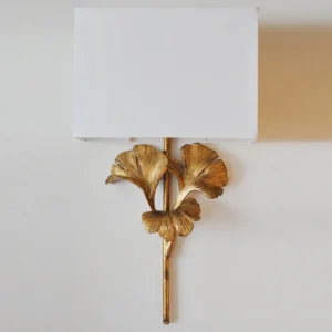 Close-up detail of gingko wall lamp showing polished brass leaf frame and rectangular fabric shade