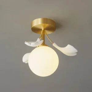 Close-up detail of unlit frosted glass shade with three white ginkgo leaf accents on ceiling fixture