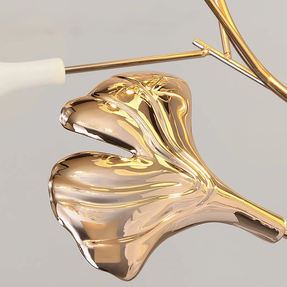 Close-up detail of Ginkgo Leaf Floor Lamp ceramic leaves and brass-tone metal branches, polished reflective surface macro shot