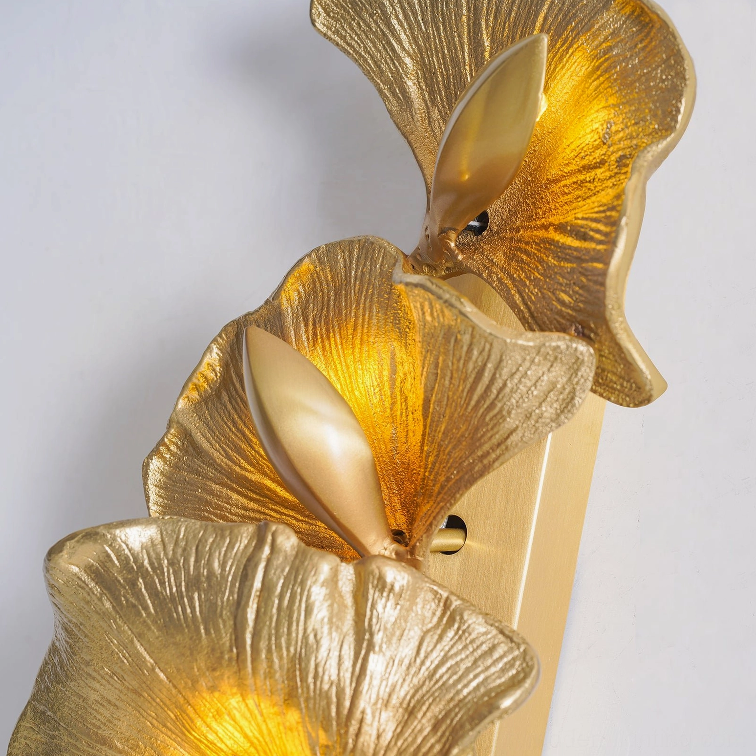 Ginkgo leaf wall sconce illuminated warm light botanical design sculptural brass leaves