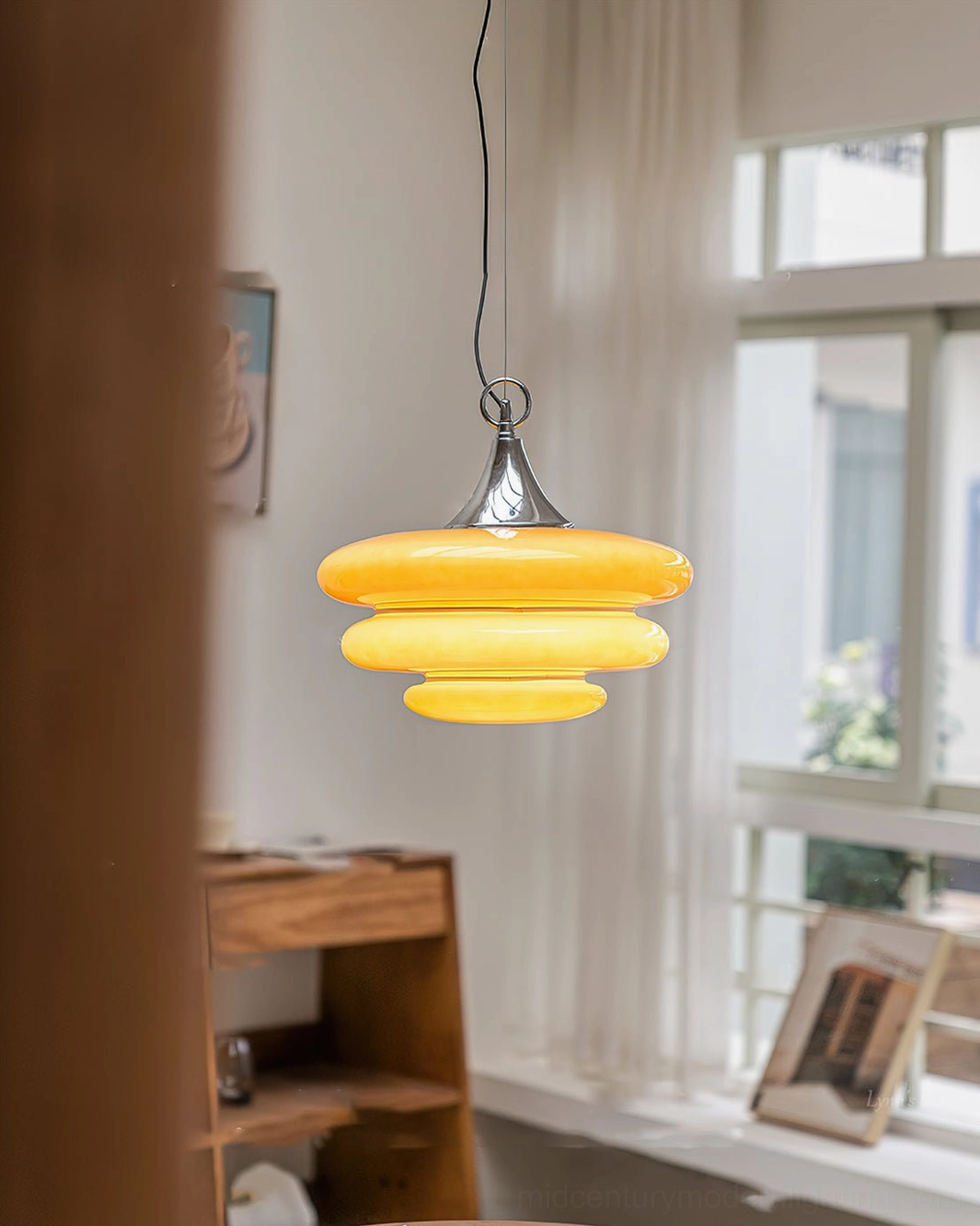 Glowing orange tiered pendant light warm illumination modern glass fixture window nook setting