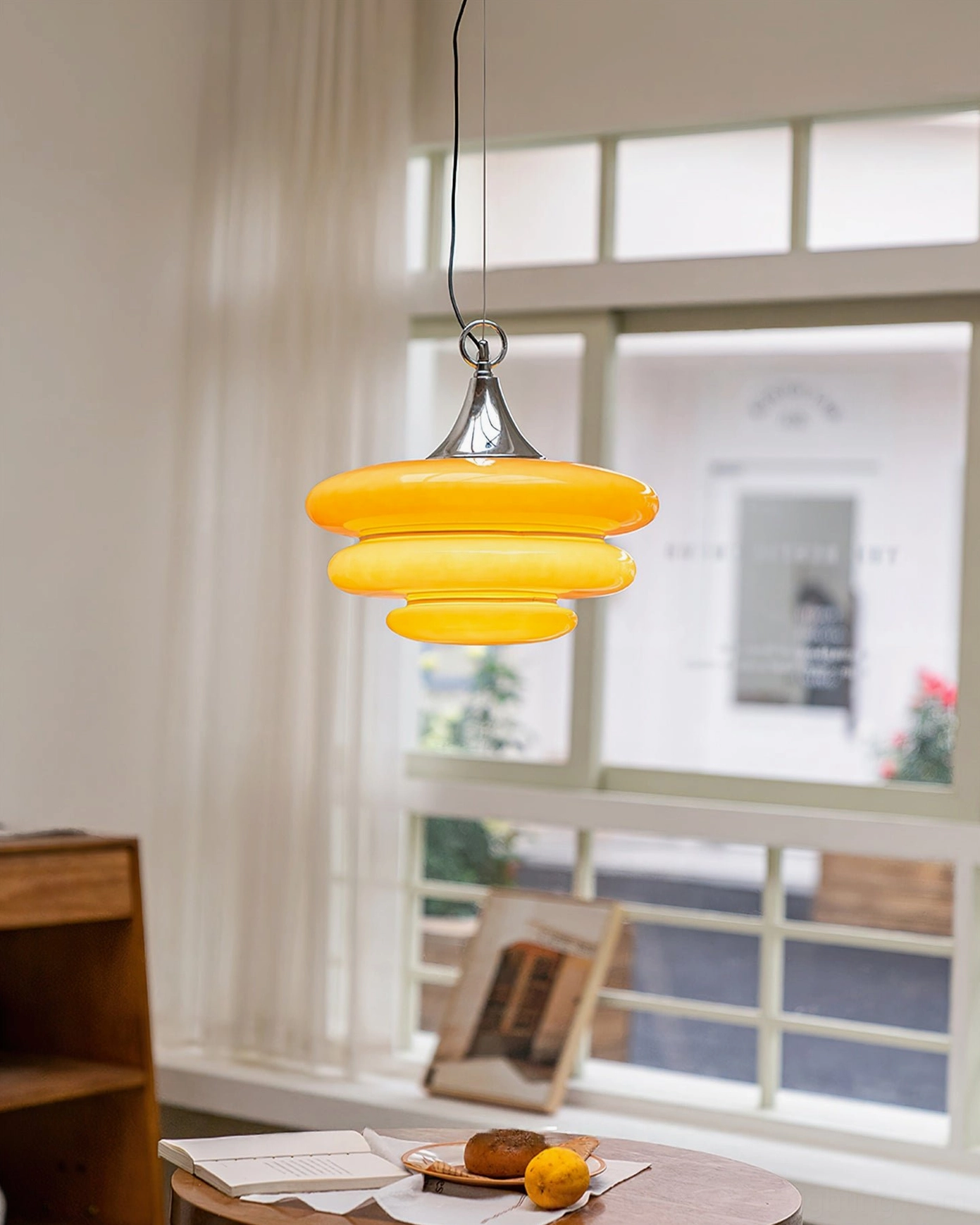 Illuminated warm yellow glowing orange tiered pendant breakfast nook bright residential setting natural light