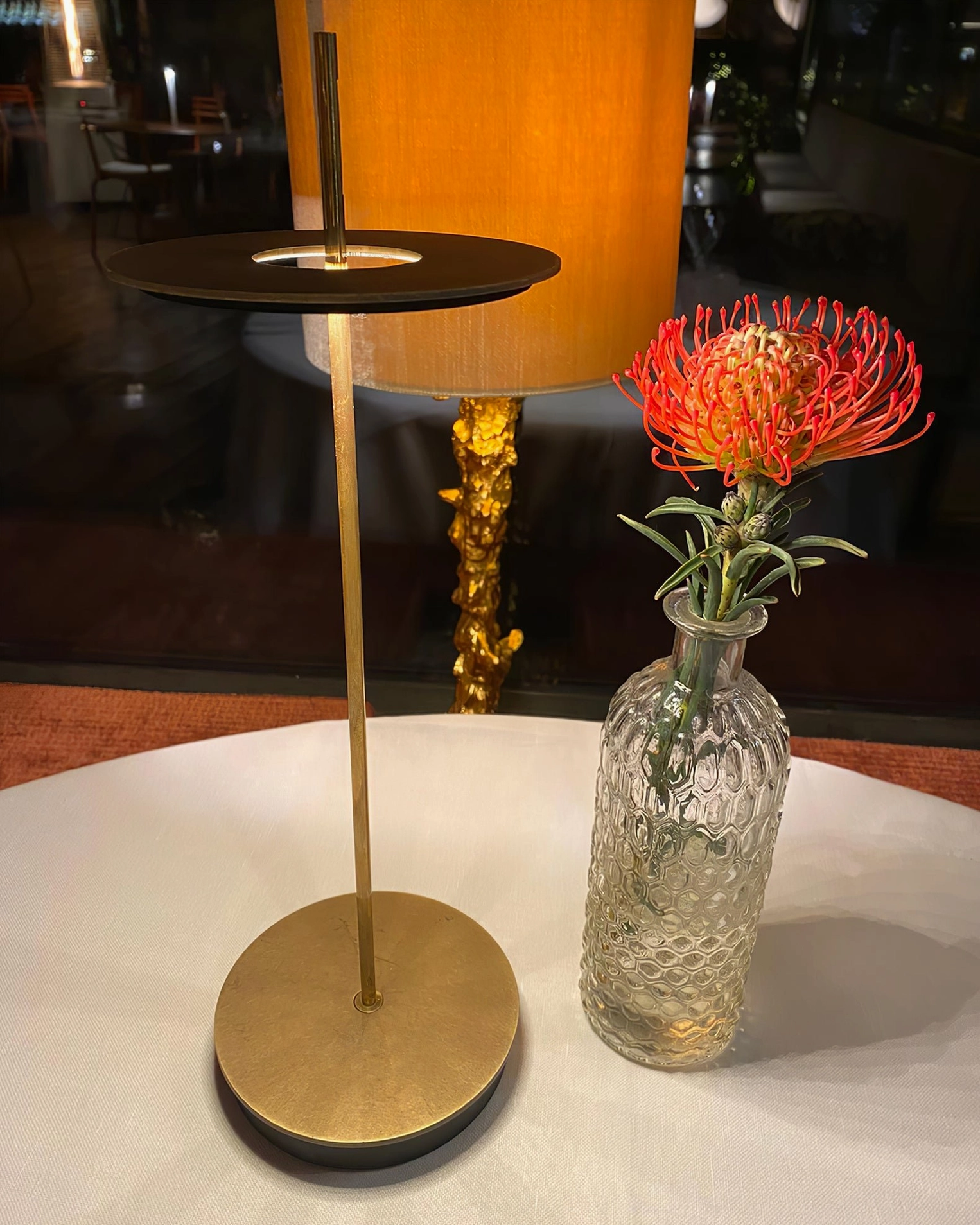 Polished brass Giulietta disc lamp positioned on marble side table in luxury residential interior