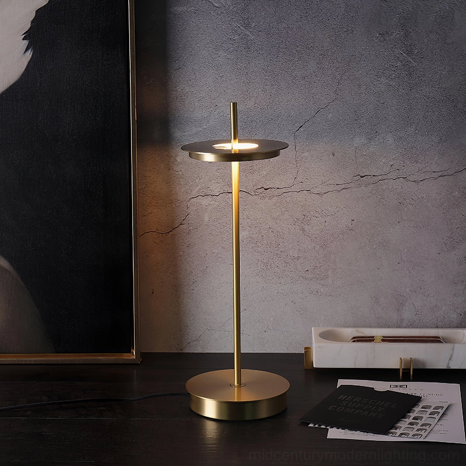 Unlit polished brass Giulietta table lamp on home office desk with wall art and minimalist modern decor