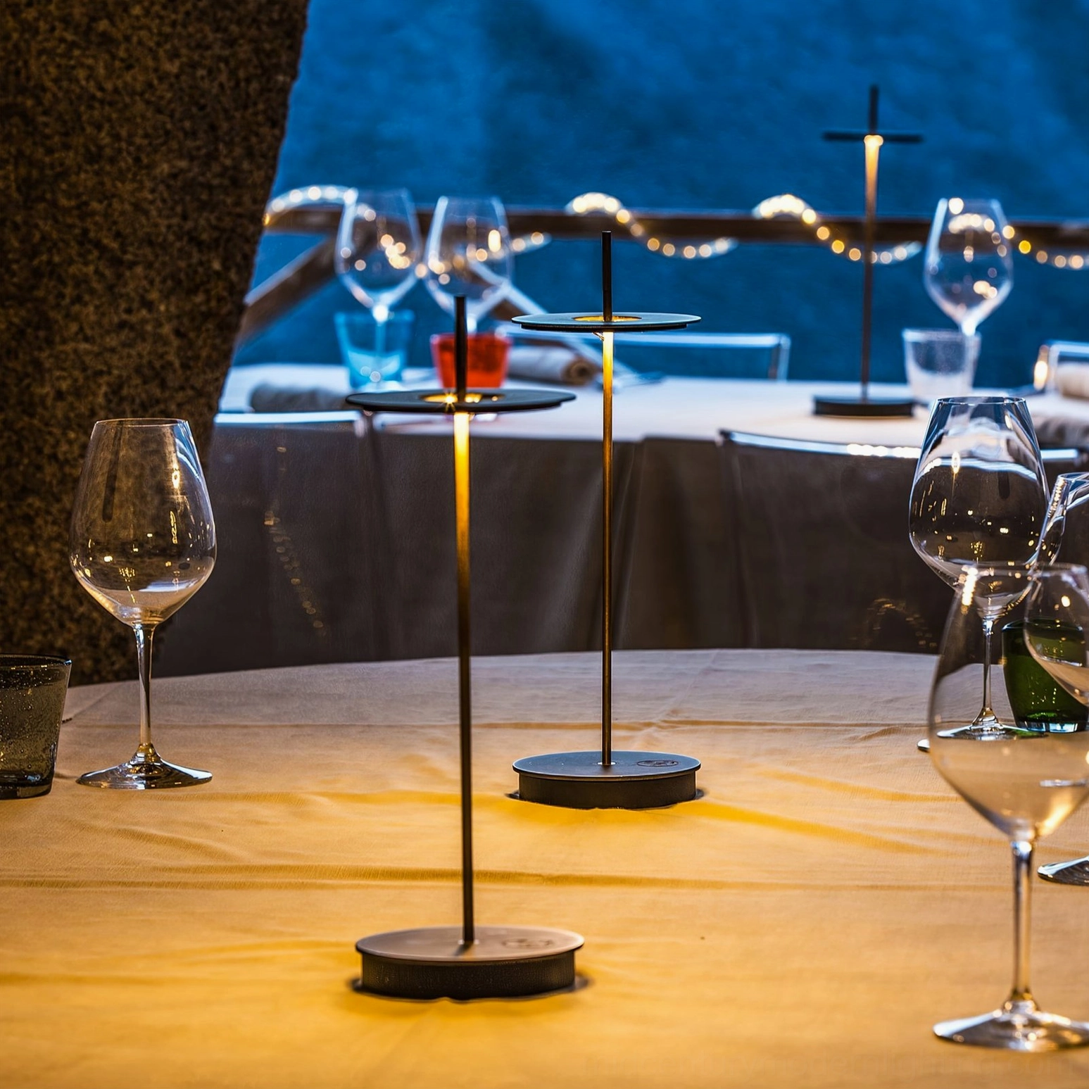Dark bronze Giulietta table lamps close-up on elegant outdoor coastal dining terrace with polished finish