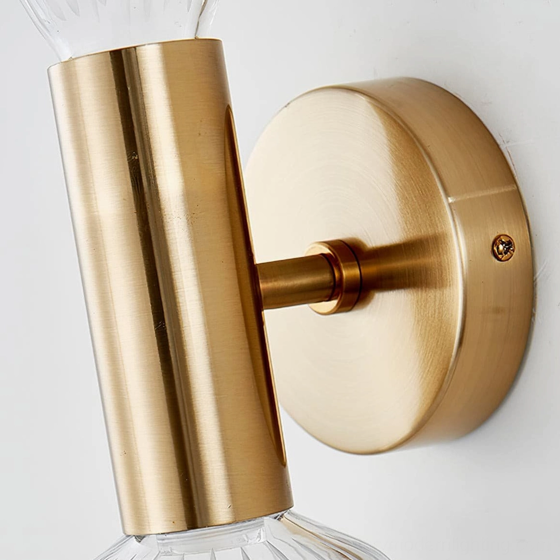 Glaive wall lamp hardware detail, brushed gold metal base mounting system, close-up studio shot