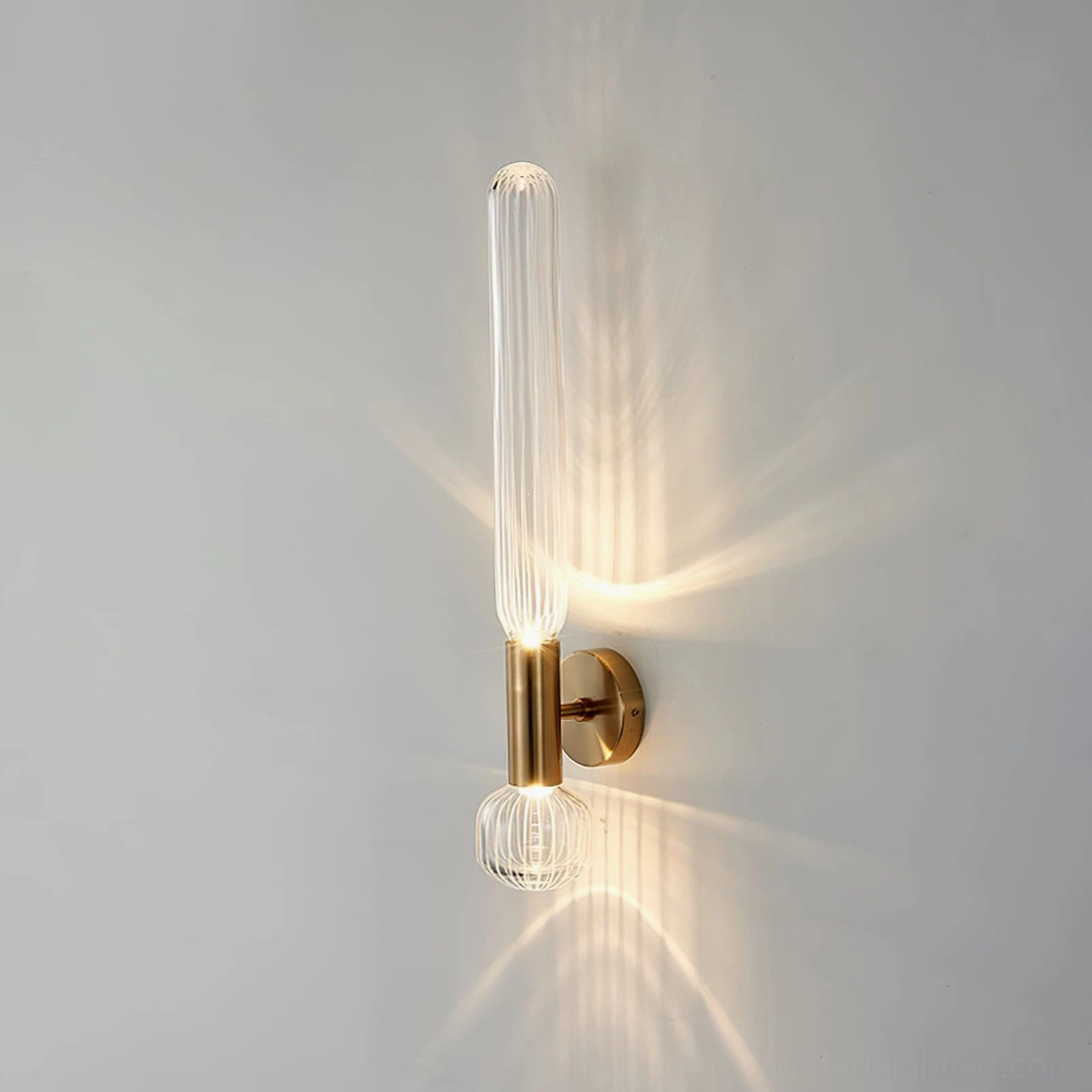 Glaive wall lamp illuminated showing warm light diffusion through ribbed glass, side view casting shadows on wall